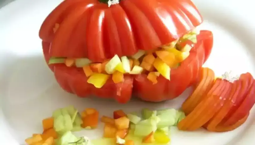 Un tomate cœur de bœuf farci de légumes croquants, servi avec des quartiers de tomate et une vinaigrette légère. Un délice estival !