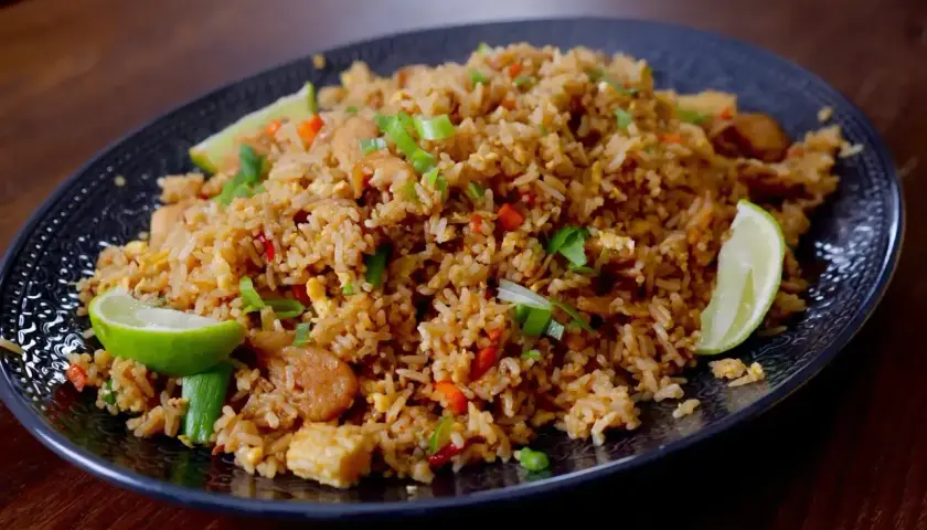 En tallrik med utsökt stekt ris, perfekt för ett snabbt och smakrikt stekt ris recept. Garnerad med limeklyftor och salladslök.
