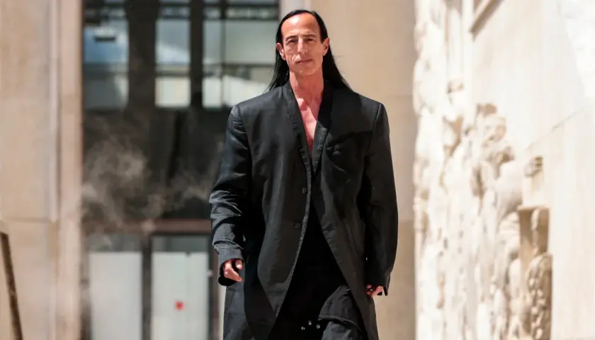 Rick Owens, w charakterystycznym czarnym płaszczu, idzie pewnym krokiem.