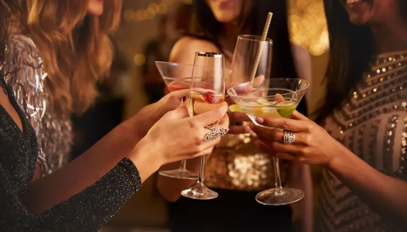 Brindis de mujeres con copas de cóctel en una celebración. La barra libre de la boda promete diversión y glamour.