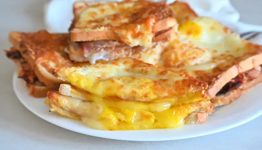 Toast filanti e dorati, preparati nella friggitrice ad aria, con formaggio fuso e un uovo.