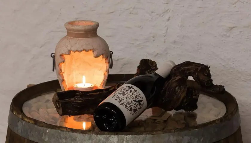 Kerzenlicht erhellt eine Flasche Wein, die auf einem Holzstück liegt. Hoffentlich wurde kein schlechten wein getrunken.