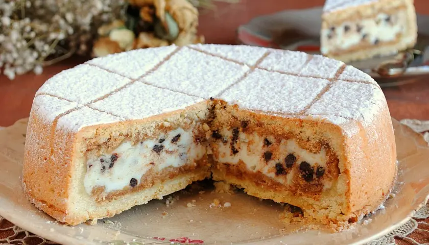 Una fetta di cassata al forno, con la sua crema bianca e gocce di cioccolato, cosparsa di zucchero a velo.