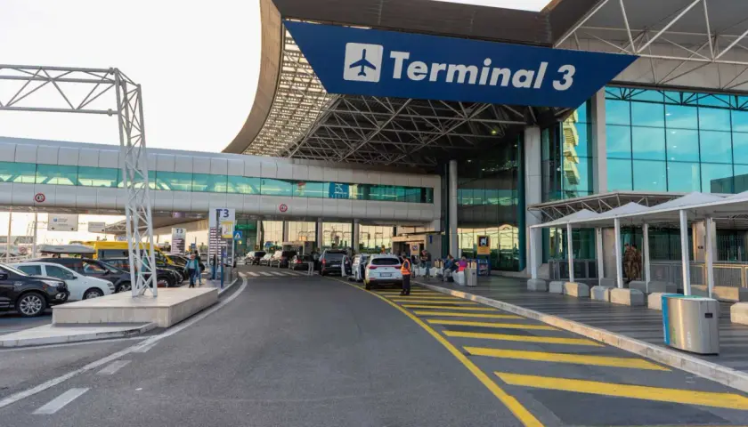 Terminal 3 lotniska Rzym Fiumicino. Samochody czekają przed wejściem, ludzie z bagażami.