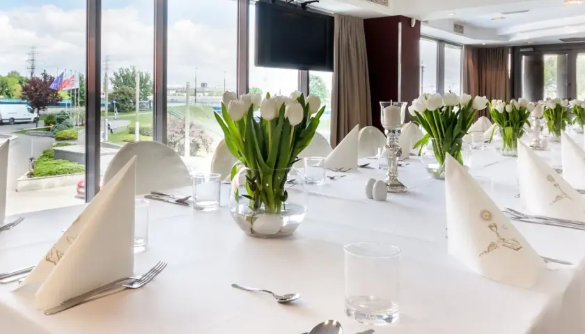Elegancko nakryty stół z białymi tulipanami, idealny na uroczystość. Zastanawiasz się, ile trwa komunia w restauracji? To zależy od wielu czynników, ale zazwyczaj trwa kilka godzin.