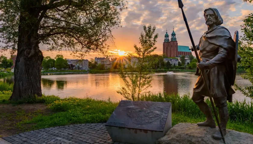 Pomnik wojownika na tle jeziora i katedry. Wschód słońca nad Gnieznem, pierwszą stolicą Polski.