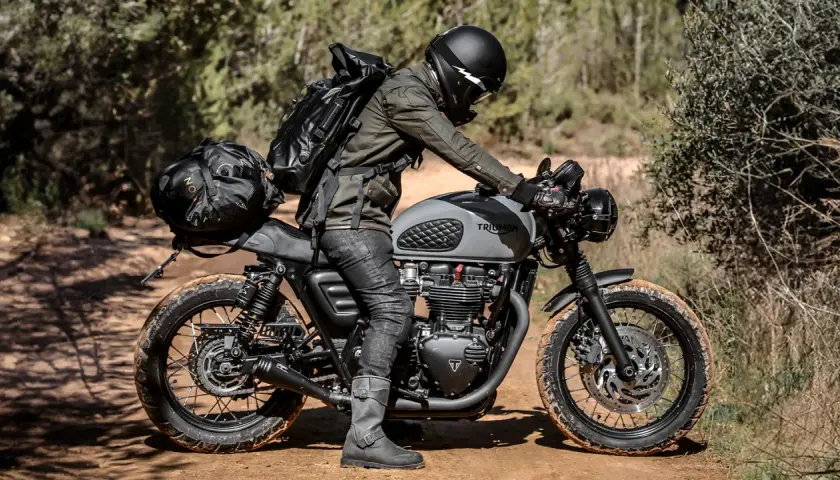 Motociclista con zaino e borse moto custom, pronto per un'avventura su sterrato.