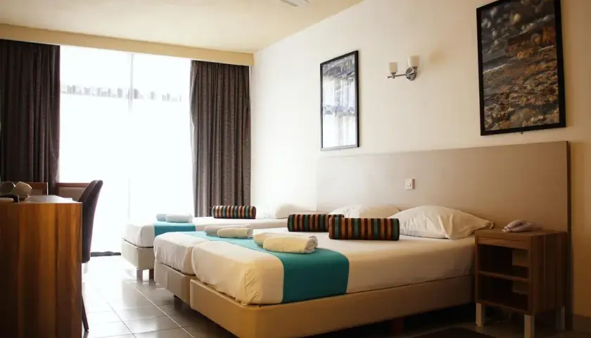 Pokój w hotelu Canifor Malta z dwoma łóżkami, zasłonami i widokiem na zewnątrz.