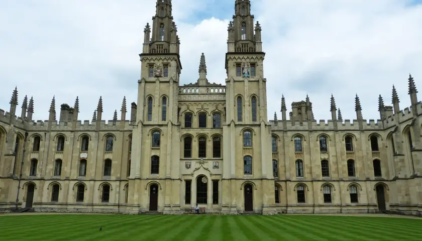 Imponująca architektura **Oxford uczelnia** z dwoma wieżami i zadbanym trawnikiem.
