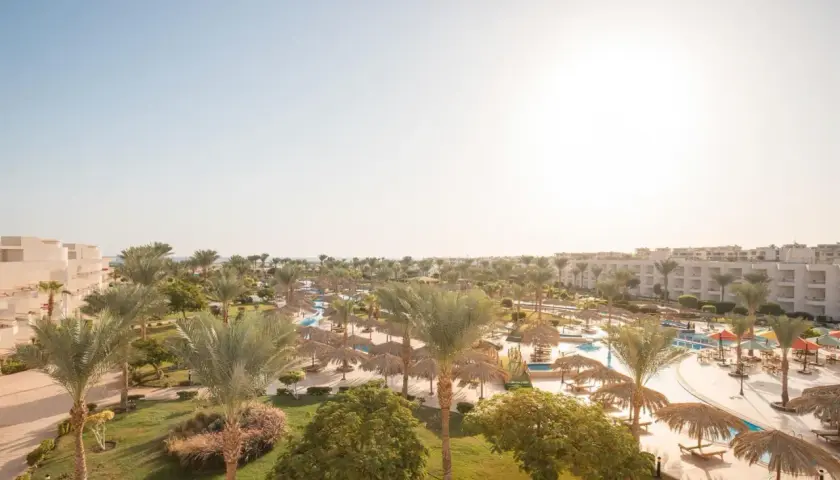 Słoneczny dzień w kurorcie Long Beach Resort Hurghada. Palmy, baseny i leżaki pod strzechą zapraszają do relaksu.