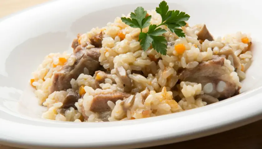 Delicioso arroz con champiñones y trozos de carne, adornado con perejil fresco.