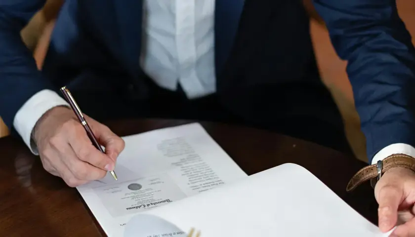 Persona firma un contrato laboral con un bolígrafo de oro.