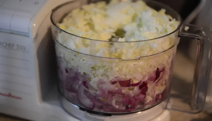 En matberedare fylld med strimlad vitkål och rödlök, redo för en härlig tre veckors sallad.