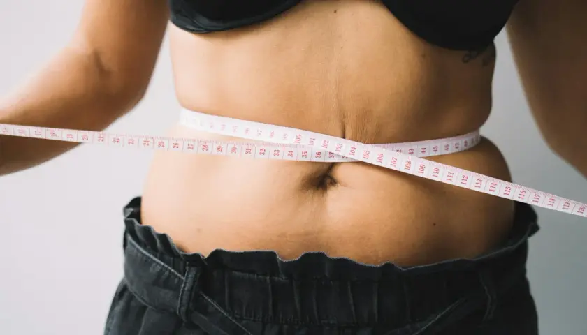 Kobieta mierzy talię centymetrem. Czy to początek drogi, jak szybko schudnąć 20 kg?