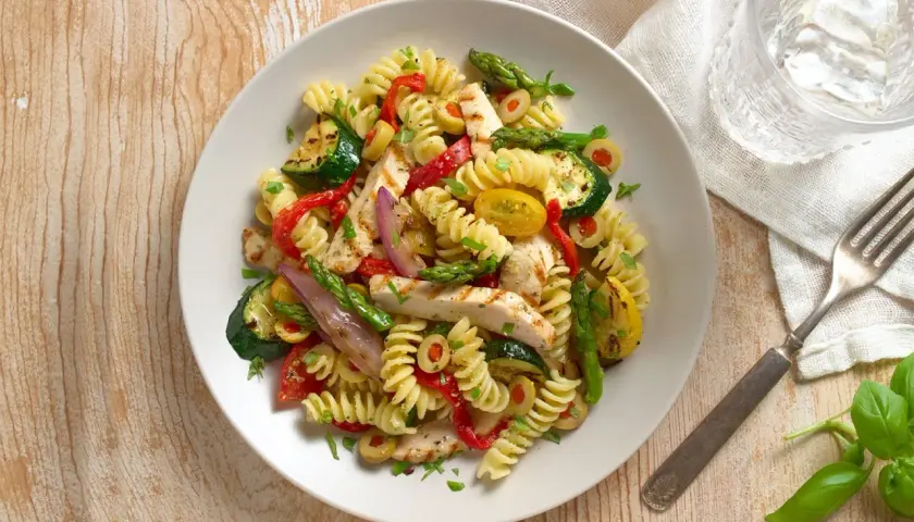 Sabrosa ensalada de pasta con pollo a la parrilla, calabacín, pimientos rojos, espárragos y aceitunas.