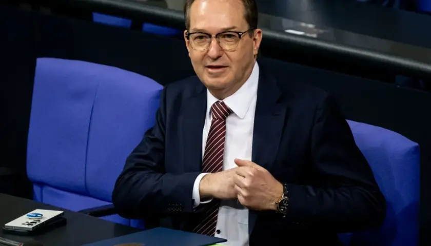 Ein Mann mit Brille und Krawatte sitzt im Bundestag. Er wirkt nachdenklich, während er seine Hände faltet. Viele Bundestagsabgeordnete sind Beamte.