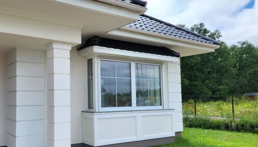 Frisch gestrichene weiße Fassade mit Fenster und Säulen.