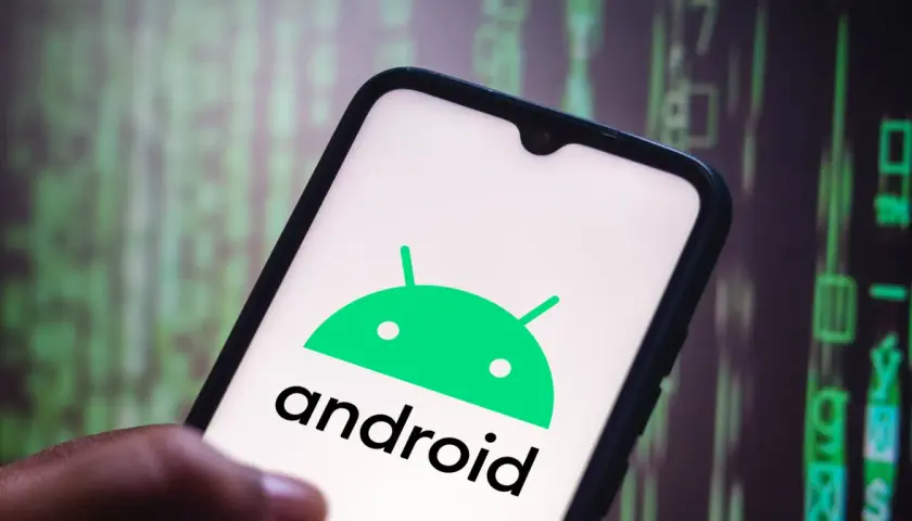 Dłoń trzyma smartfon z logo Android 10. Tło to zielony, rozmyty kod.