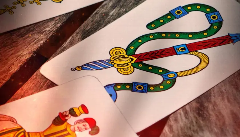 Carte da gioco napoletane, tra cui il sette di spade e un personaggio. Immagina come si gioca a cucù con queste carte!