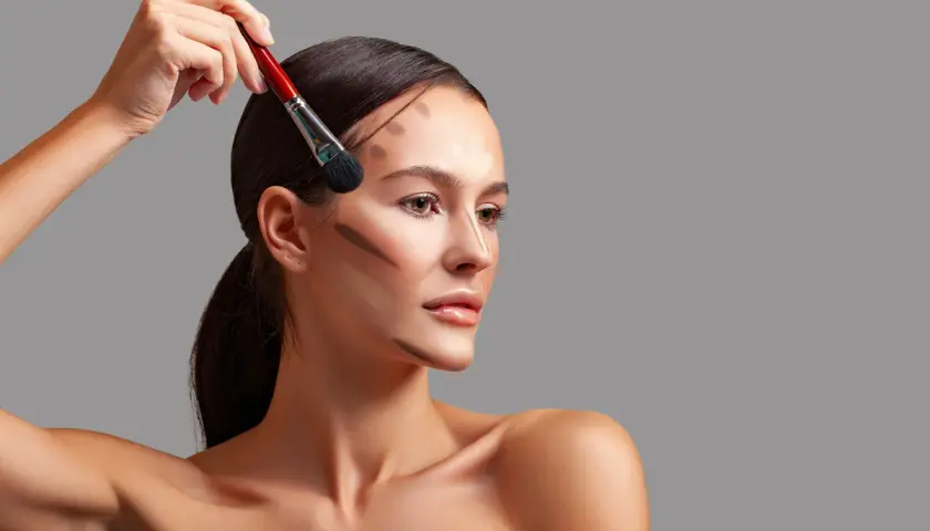 Modelka z pociągnięciami bronzera na twarzy, pokazującymi, do czego służy bronzer: podkreślenia rysów i nadania głębi.
