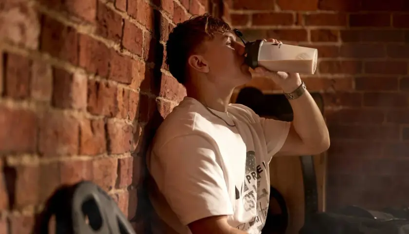 Junger Mann trinkt aus Shaker, bereit für die Kreatin Aufladephase.