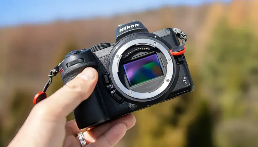 Dłoń trzyma aparat Nikon Z5 bez obiektywu, ukazując sensor. Trwa test tego modelu.