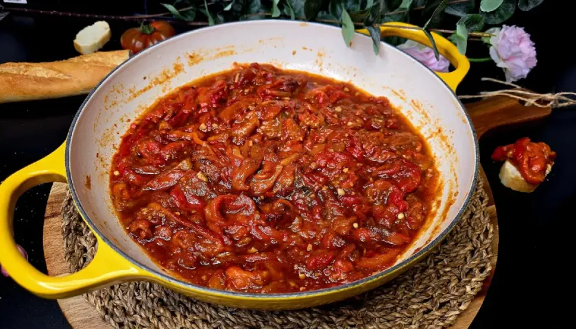 Asadillo manchego recién hecho en sartén amarilla, acompañado de pan y tomates.