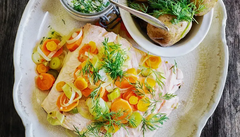 En vacker portion inkokt lax med morötter, purjolök och dill. Serveras med kokt potatis och en krämig sås.
