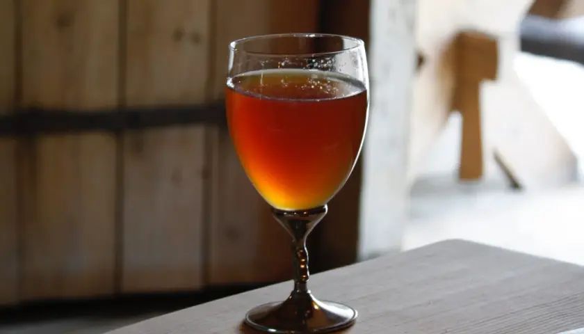 Verre de bière norvégienne ambrée, posé sur une table en bois.
