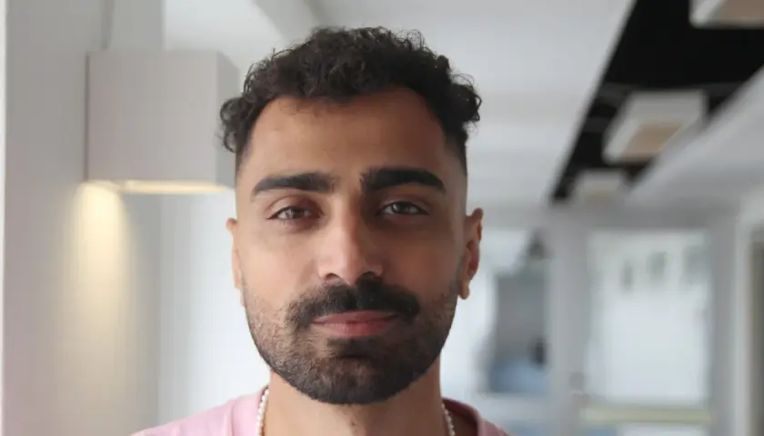 Alexander Abdallah, en ung man med lockigt mörkt hår och skägg, tittar rakt in i kameran.