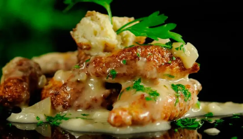 Deliciosas albóndigas de rape doradas, cubiertas con una cremosa salsa y perejil fresco. Un plato que invita a probar.