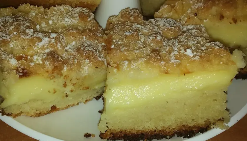 Pyszne ciasto drożdżowe z budyniem, posypane cukrem pudrem. Idealne na deser!