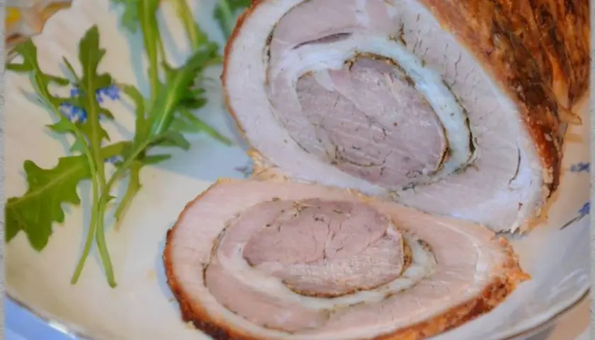 Pyszna rolada z boczku, pieczona do złotego koloru, z soczystym wnętrzem i chrupiącą skórką. Podana z rukolą.