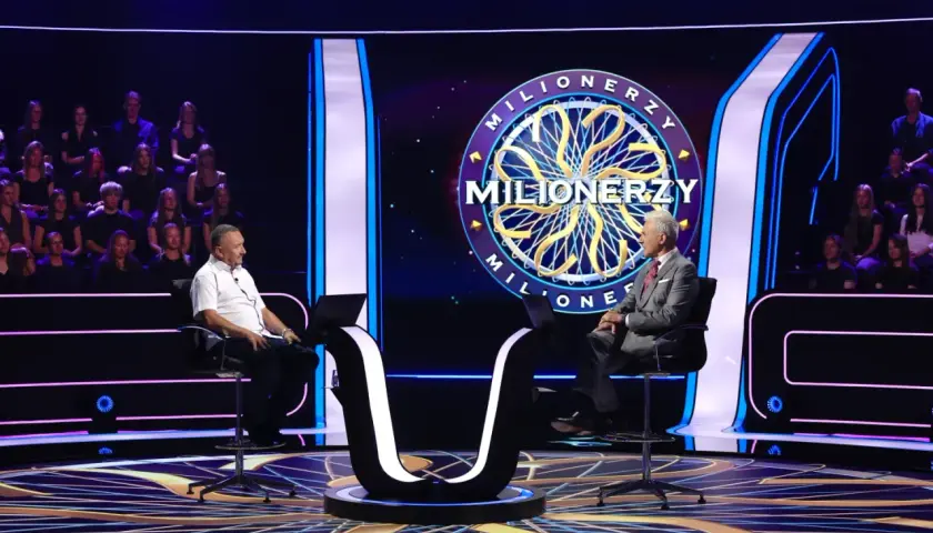 Oszczędny milioner siedzi na krześle w studiu telewizyjnym, gotowy do gry.