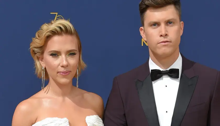 Scarlett Johansson w białej sukni i Colin Jost, jej mąż, w garniturze na czerwonym dywanie.