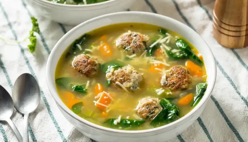 Pyszna zupa klopsowa babci z klopsikami, makaronem nitki, marchewką i szpinakiem w aromatycznym bulionie.