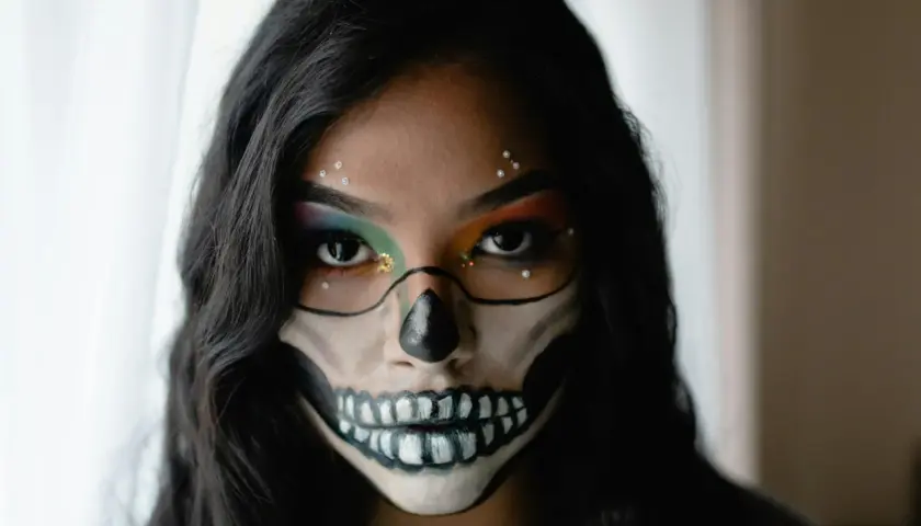 Makijaż na Halloween w stylu sugar skull: czarne kontury czaszki, kolorowe cienie do powiek i błyszczące dżety.