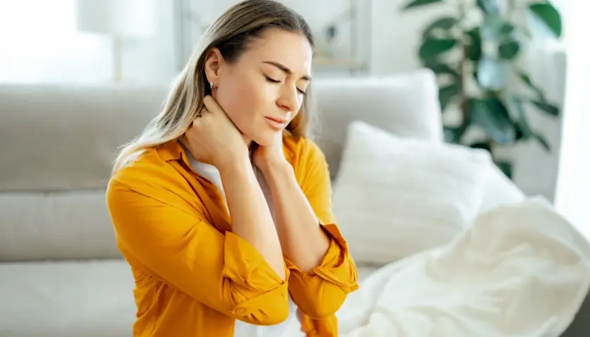 Donna con occhi chiusi e mani sul collo, soffre di dolori muscolari diffusi.