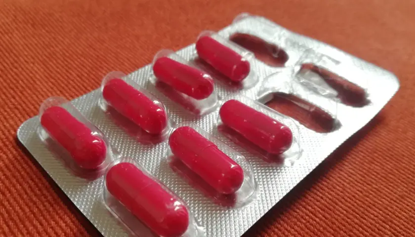 Czerwone kapsułki w blistrze. Może to suplement diety, np. cynk na co dzień, dla wzmocnienia odporności.