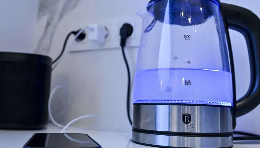 Ein beleuchteter Wasserkocher steht neben einem Smartphone. Ein Tipp: Wasserkocher entkalken Backpulver hilft gegen Kalk.