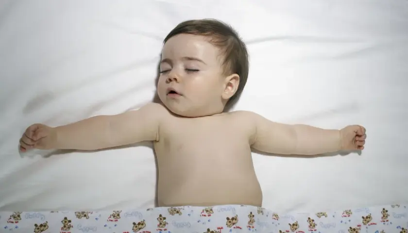 Śpiące dziecko z rozłożonymi rączkami. Choć obrazek nie sugeruje zespołu Turnera, warto pamiętać o jego istnieniu.