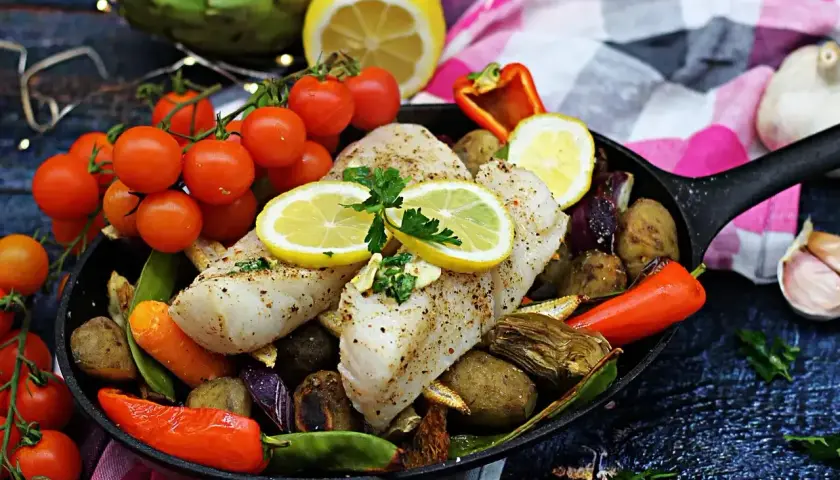 Pyszny halibut ryba pieczony z warzywami i cytryną na patelni.