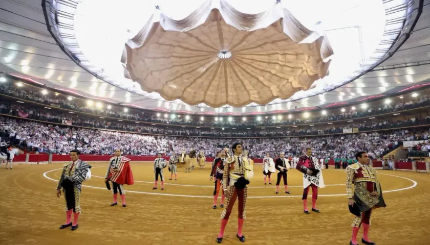 Toreros listos en una de las plazas de toros cubiertas en España, con público en las gradas y un techo desplegable.
