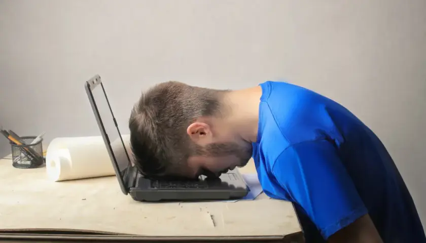 Frustrierter Mann mit Kopf auf Laptop. Er sucht nach einem Musterbrief für den Widerruf einer Abo-Falle.