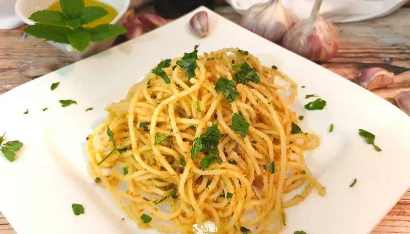 Pyszne spaghetti aglio e olio, posypane natką pietruszki, z czosnkiem i oliwą w tle.