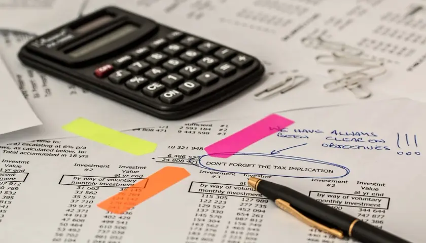 Kalkulator, notatki i dokumenty finansowe. Na jednym z nich widnieje napis "DON'T FORGET THE TAX IMPLICATION", co może sugerować podatek od zasiedzenia.