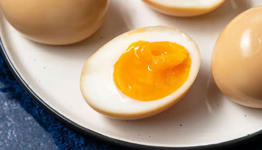 A plate of perfectly cooked onsen eggs, some whole and some halved to reveal their creamy, golden yolks.