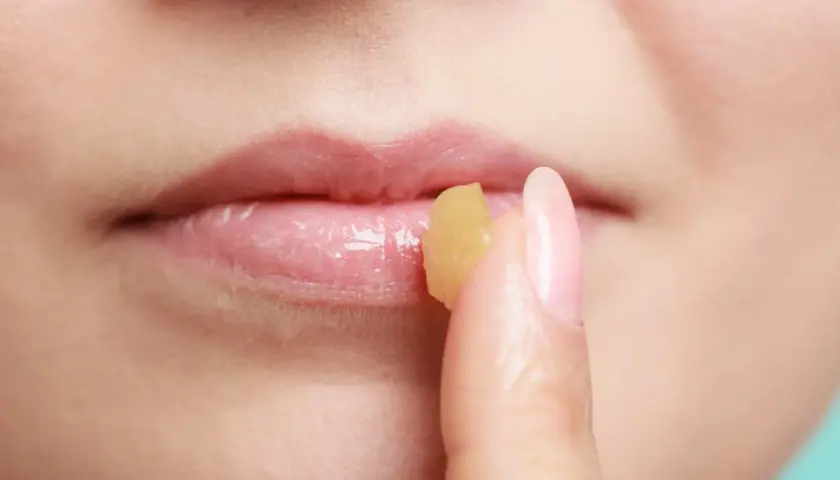 Dita applica un balsamo sulle labbra, un rimedio della nonna per labbra infiammate.