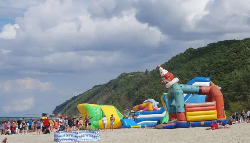 Kolorowe dmuchańce na plaży w Międzyzdrojach to świetne atrakcje dla dzieci. Wesoły klaun zaprasza do zabawy.