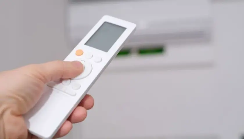 Mano sujetando control remoto para aprender como poner aire acondicionado en frio.